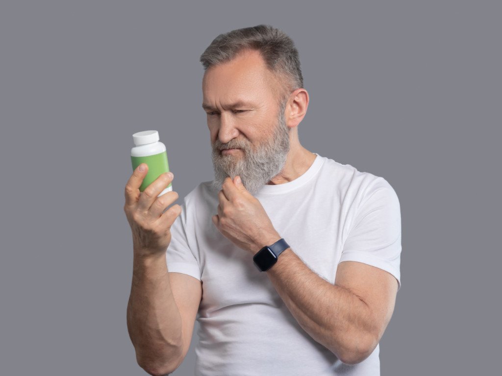 Man carefully examining natural weight loss supplements bottle label to assess safety and ingredients before use