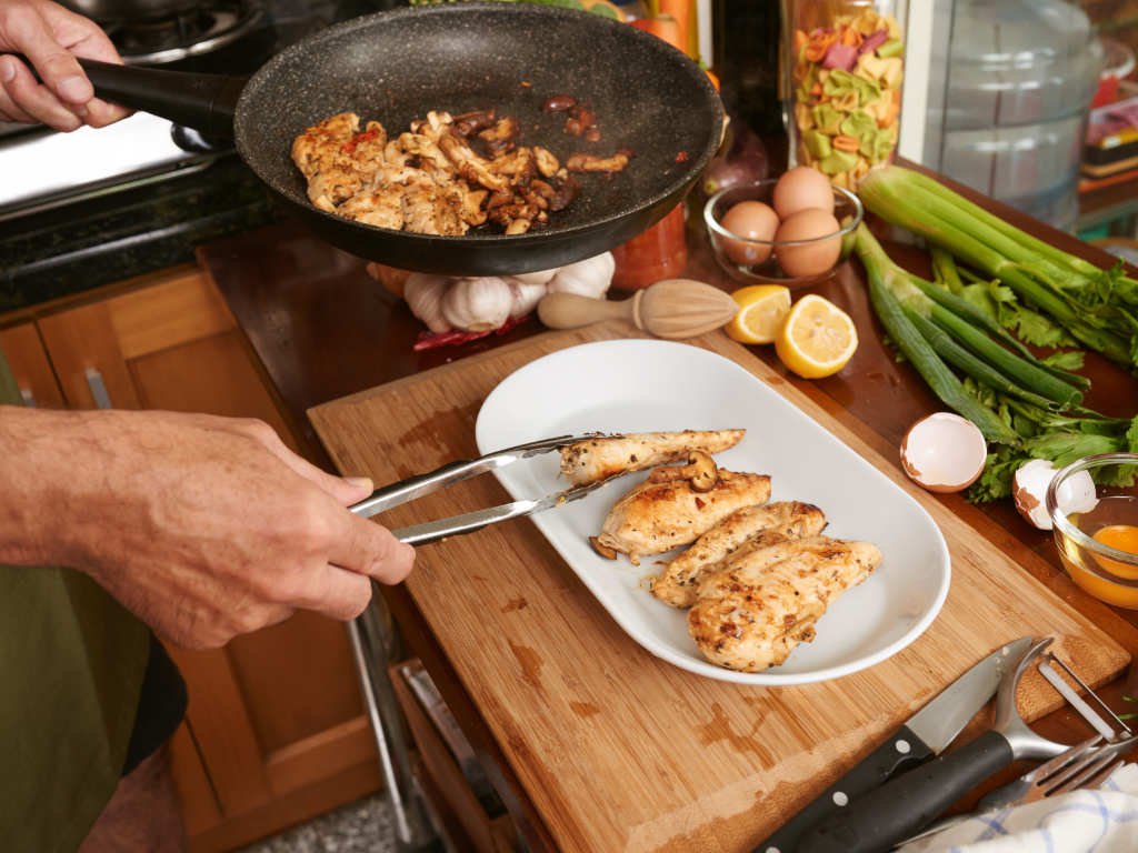 Hands-on meal planning strategy showing diverse fresh ingredients being cooked including chicken, mushrooms, vegetables and eggs for optimal health