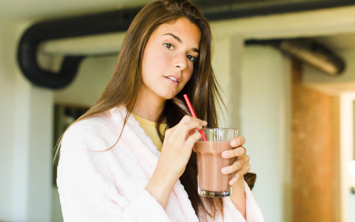 Woman with glowing skin enjoying nutrient-dense smoothies for skin health in modern kitchen