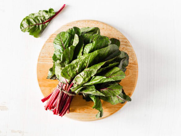 Bunch of fresh Swiss chard on wooden cutting board featuring leafy superfoods for daily nutrition