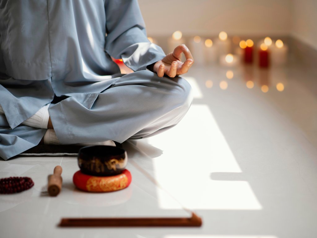 Person demonstrating proper Zen meditation techniques in lotus position with traditional singing bowls and incense in serene candlelit setting