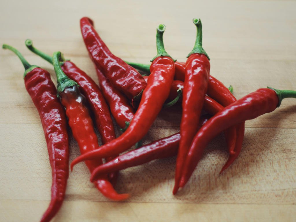 Fresh red cayenne peppers on wooden surface representing metabolism boosting spices for natural fat burning and weight loss