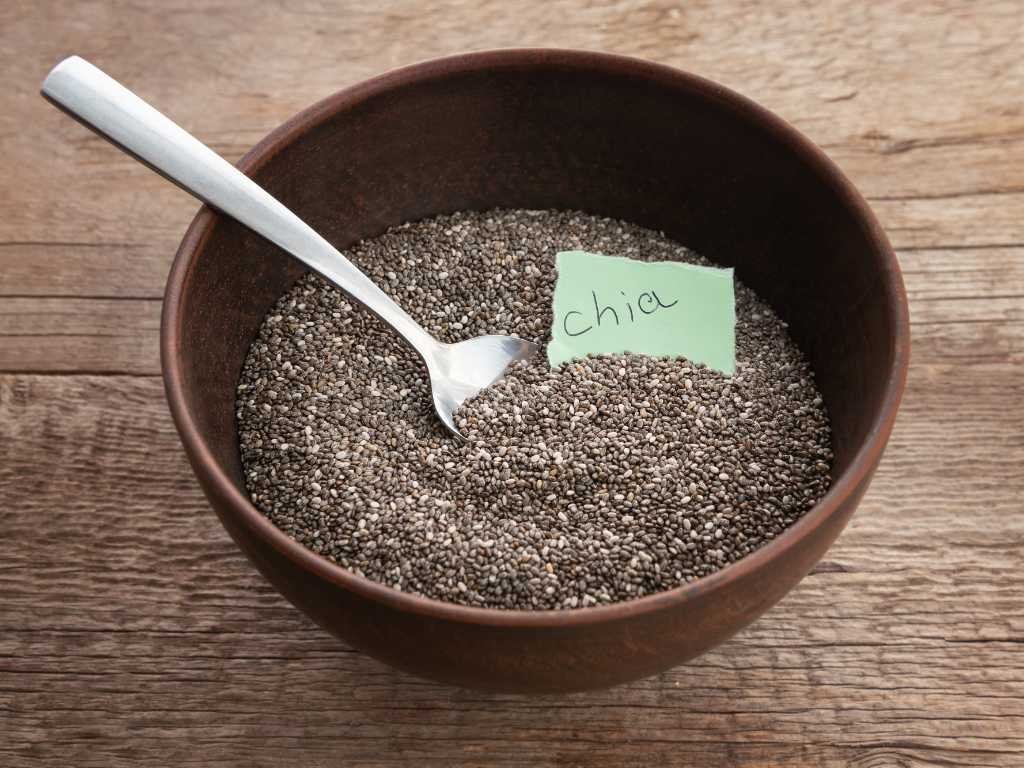 Bowl of chia seeds with wooden spoon and label, superfoods for metabolism and morning nutrition