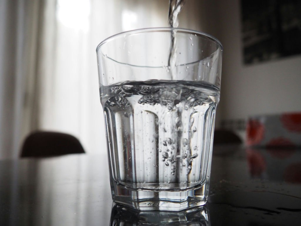 Fresh water being poured into glass demonstrating consistent daily hydration habits for enhanced skin beauty and health