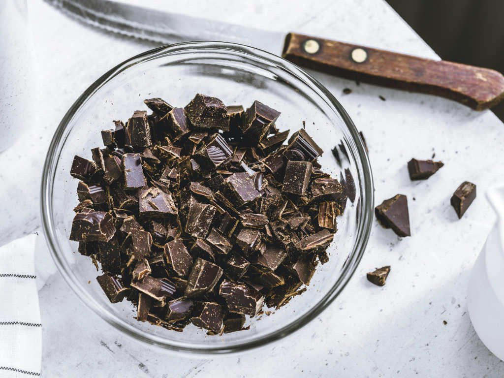 Chopped dark chocolate pieces in glass bowl - key ingredient for antioxidant snacks like chocolate-covered almonds