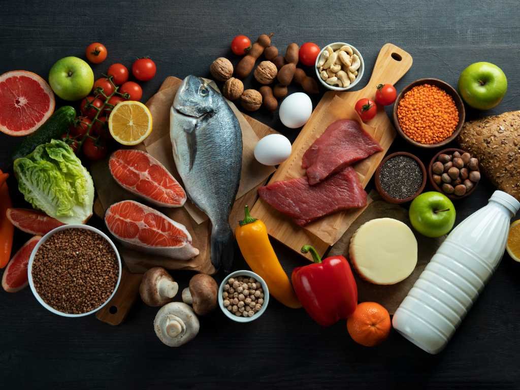 Essential nutrients B vitamins energy production foods including fish, lean meat, eggs, leafy greens, legumes, nuts and whole grains arranged for optimal physical and mental performance