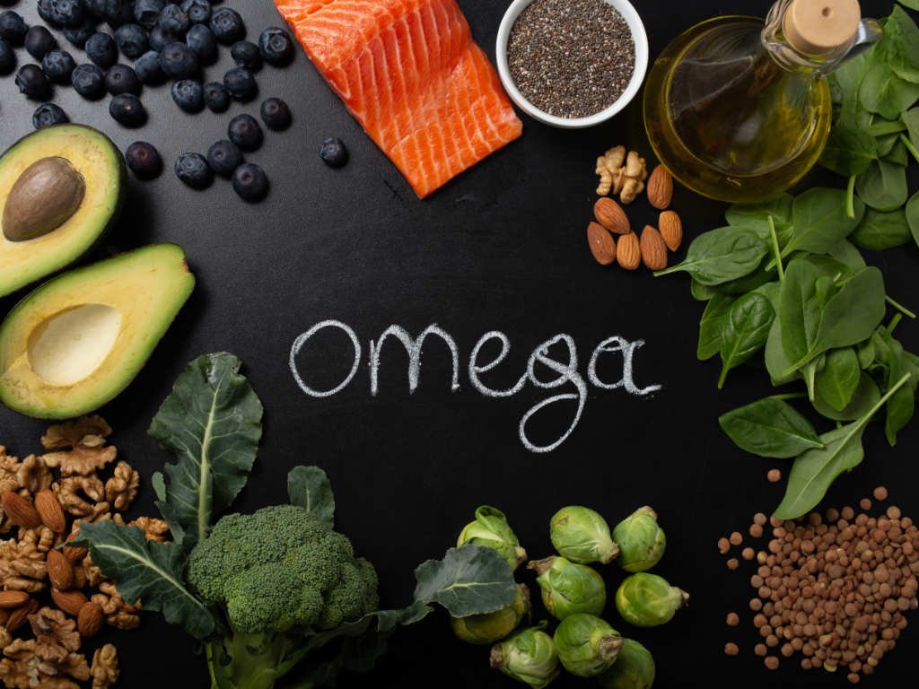 Essential nutrients omega-3 fatty acids brain food sources including salmon, avocado, walnuts, chia seeds, and leafy greens arranged around omega text for optimal mental performance