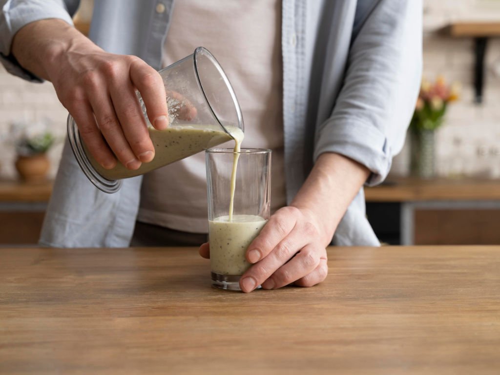 Person pouring fresh plant protein smoothie made with nut milk - healthy plant-based protein snacks for energy and post-workout muscle recovery