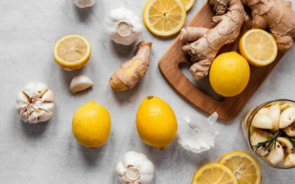 Essential superfoods for immunity including fresh lemons, ginger root, and garlic cloves arranged on marble surface with wooden cutting board