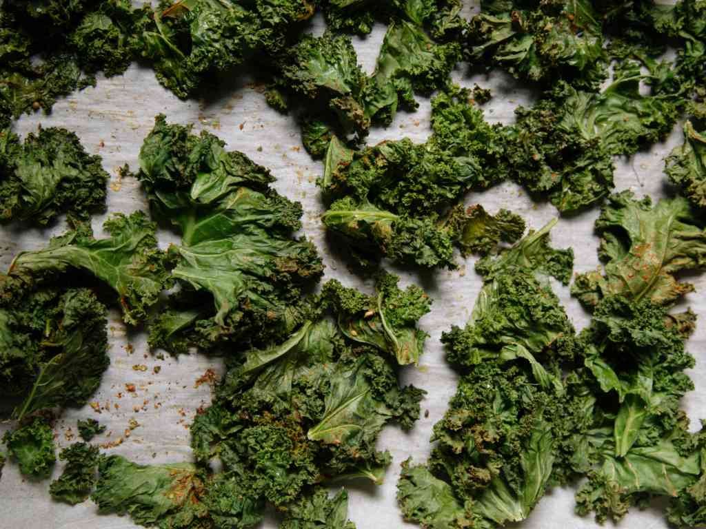 Crispy homemade kale chips on parchment paper - healthy antioxidant snacks for active individuals