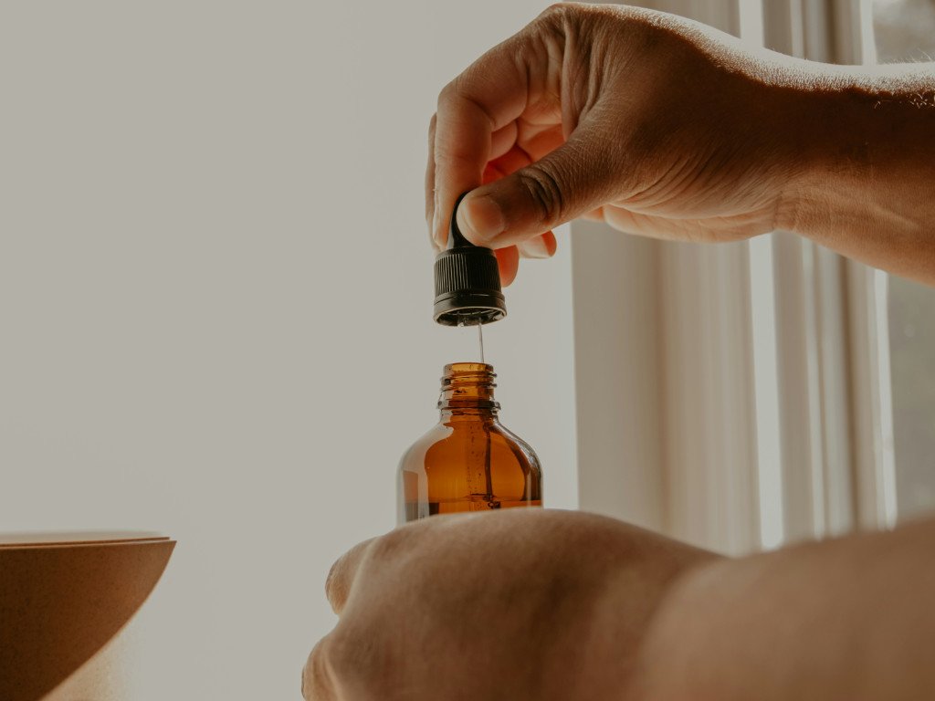 Hand dispensing liquid multivitamins from amber dropper bottle, showing how to take liquid form multivitamins for daily health benefits