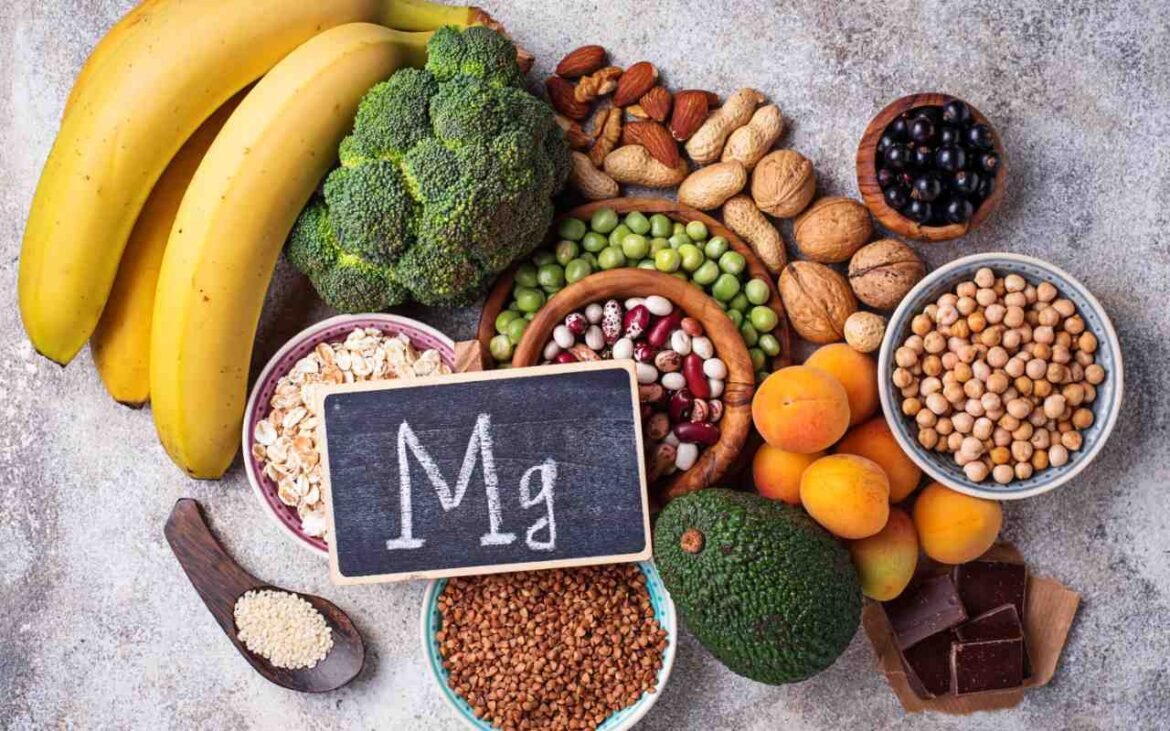 Various magnesium insufficiency prevention foods including bananas, broccoli, nuts, legumes, and dark chocolate arranged around Mg chalkboard sign
