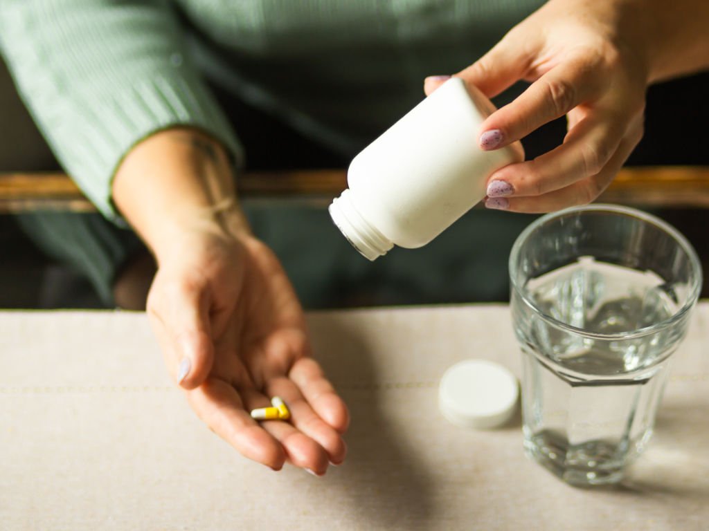 Person taking melatonin capsule as natural sleep aids for better rest and sleep regulation