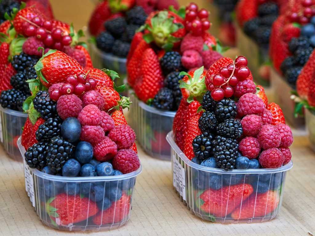 Fresh mixed berries in plastic containers including strawberries blueberries and raspberries, antioxidant-rich superfoods for metabolism