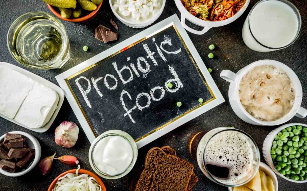 Probiotic-rich foods including kefir, yogurt, fermented vegetables, and pickles arranged around a chalkboard sign reading "Probiotic food" - complete guide to gut health boosting foods