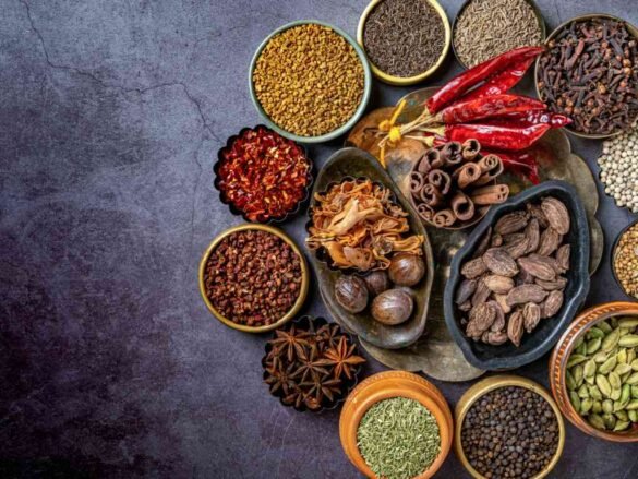 Assorted staple foods including whole spices, seeds, and dried chilies arranged in bowls - essential flavor arsenal for healthy cooking