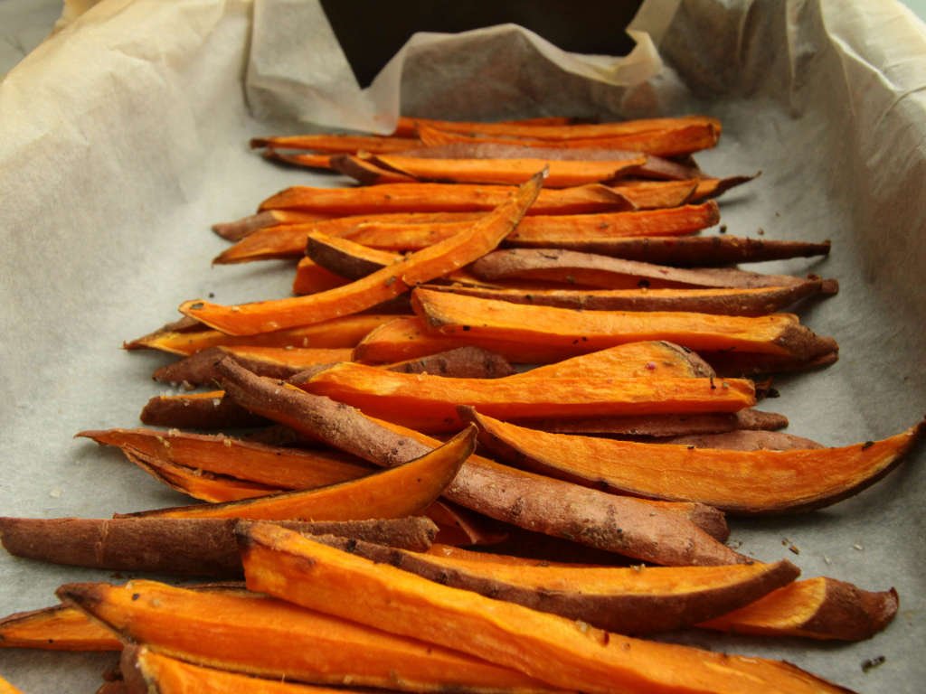 Baked sweet potato fries on parchment paper - healthy complex carb antioxidant snacks for active individuals