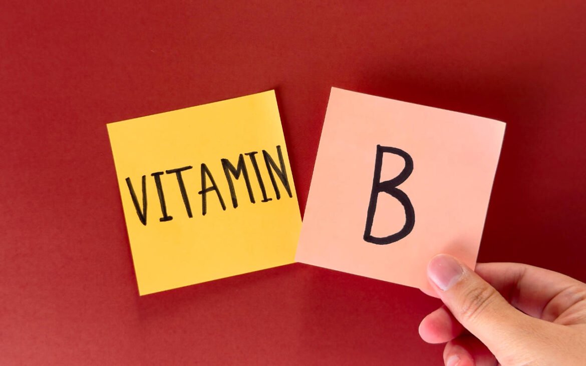 Hand holding sticky notes with "Vitamin B" text on red background - comprehensive guide to vitamin B types and benefits