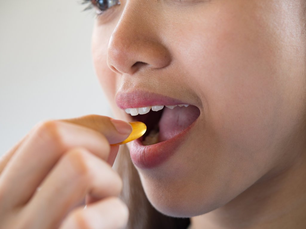 Person taking high-quality vitamin B supplement capsule showing importance of supplement quality and proper intake