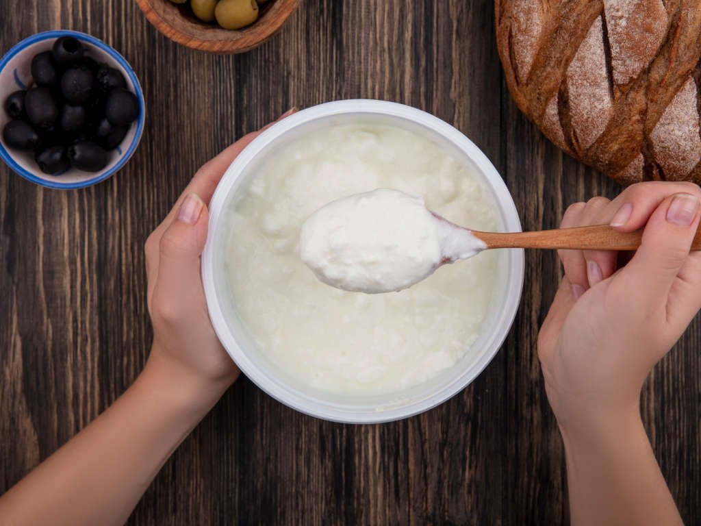 Fresh plain yogurt superfoods for immunity rich in probiotics for gut health in white bowl with wooden spoon
