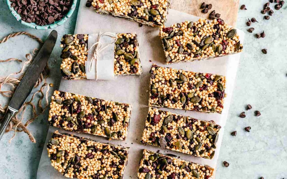Homemade protein bars with puffed quinoa, pumpkin seeds, and chocolate chips arranged on parchment paper