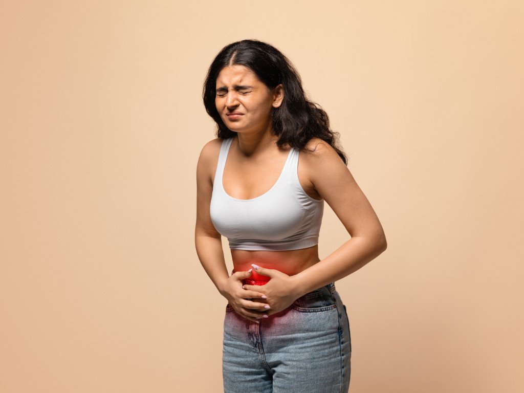 Woman experiencing stomach discomfort showing potential digestive side effects of magnesium for headaches supplementation