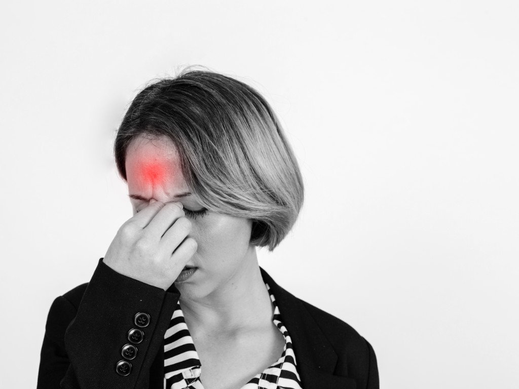 Woman with tension-type headache holding forehead showing symptoms that magnesium for headaches may relieve